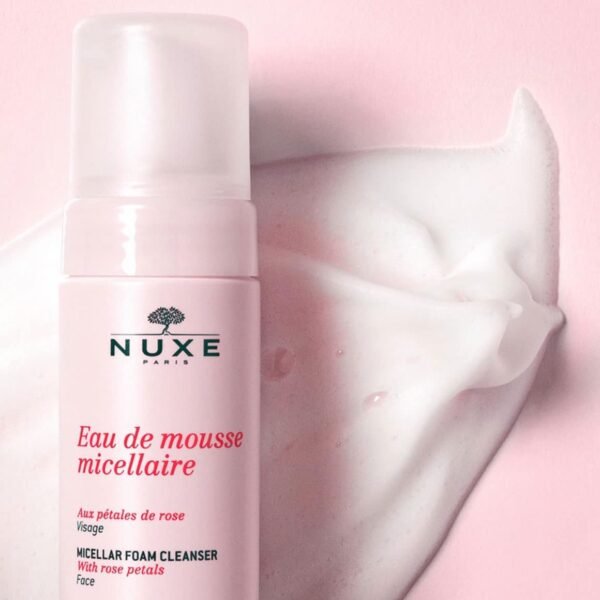 NUXE Paris pink bottle of micellar foam cleanser for the face, with rose-petal accents and a swirl of foam nearby on a pink backdrop.