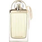 Chloé Love Story perfume bottle with a ribbed gold-tinish glass, clear cap, and a beige ribbon tied to the side.