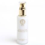 White cosmetic bottle with gold pump labeled 'Secret' and 'Oil Free Moisturizer Cream' on a clean backdrop, featuring a decorative gold emblem.