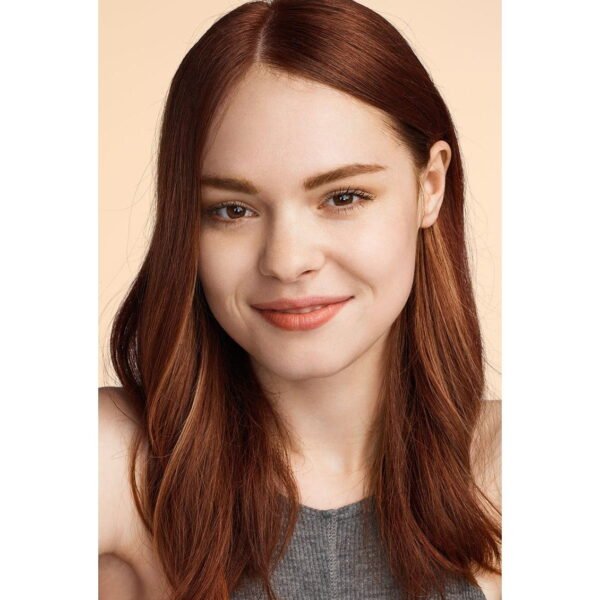 Portrait of a smiling woman with long auburn hair against a peach background, cropped at shoulders.