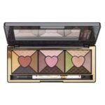 Open gold-toned eyeshadow palette with six heart-centered pans in gold, pink, purple, brown, green, and bronze, plus a liner pencil beneath.