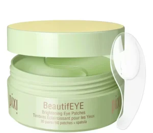 Pixi BeautifEYE Brightening Eye Patches in a pale green jar with a clear spatula resting beside it.
