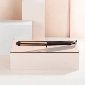 Copper-finish fountain pen resting on a pale pink box with a soft geometric backdrop behind it.